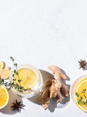 Immune boosting remedy. Flat lay  with ingredients from turmeric, thyme, lemon, star anise and glass water with lemon on white background with hard shadows. Top view, copy space